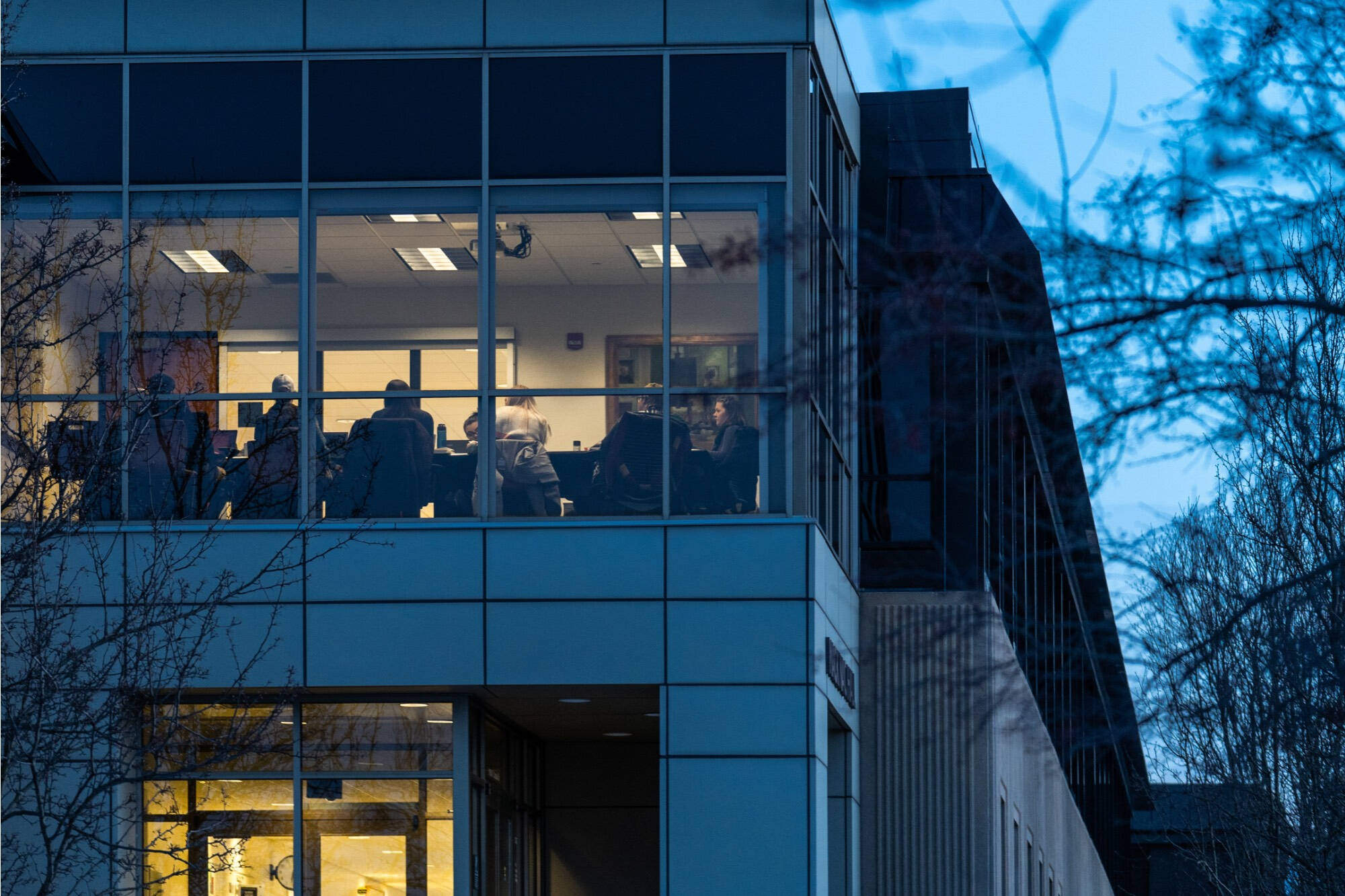 Group sitting in a large space surrounded by glass